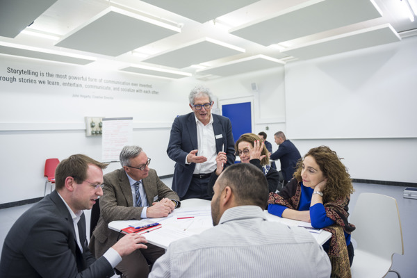 Groupe qui discutent autour d'une table accompagné du professeur