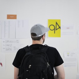 Une homme avec une casquette devant un tableau blanc rempli de feuilles